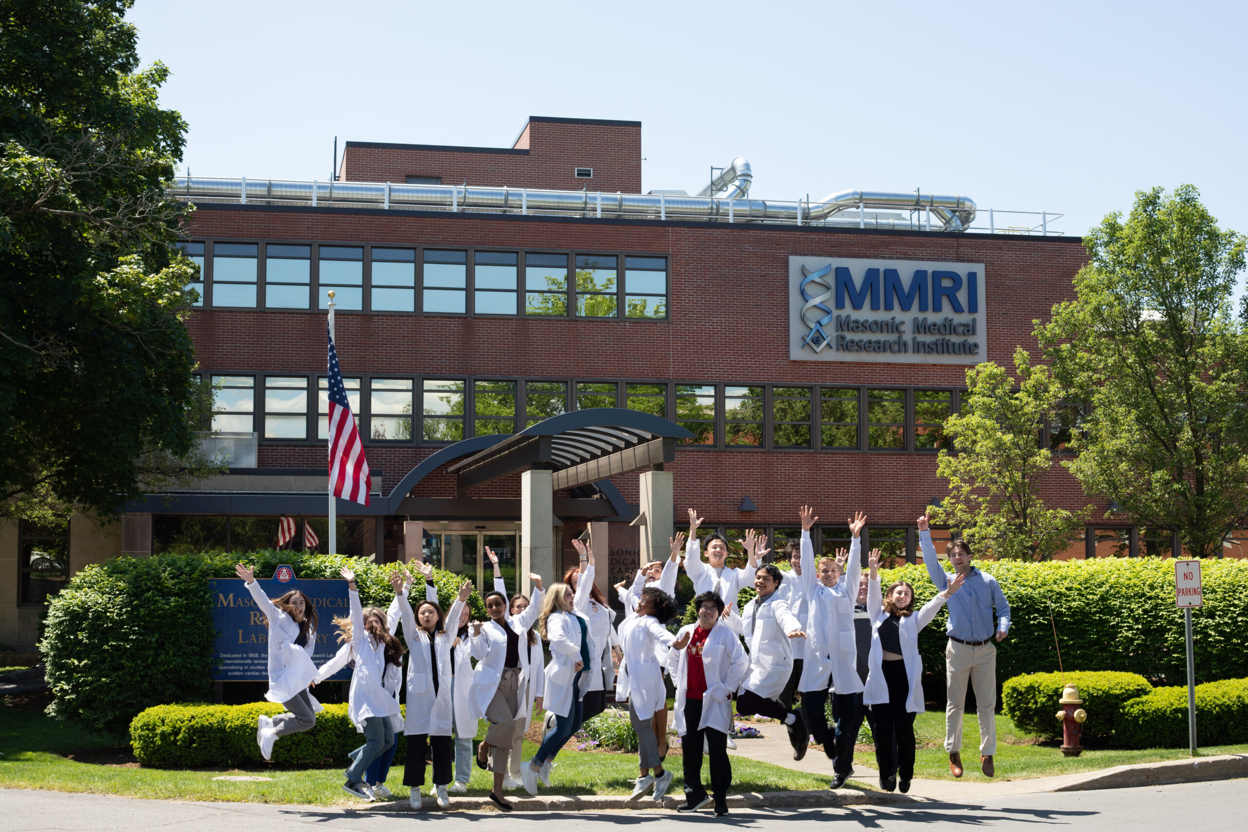 19 Summer Fellows Jumping in front of MMRI building